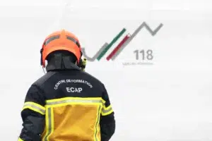 Reportage photographique pour l’ECAP – Maison du feu de Couvet Pompier de l’ECAP devant une bâche indiquant le numéro d’appel d’urgence, à la Maison du feu de Couvet